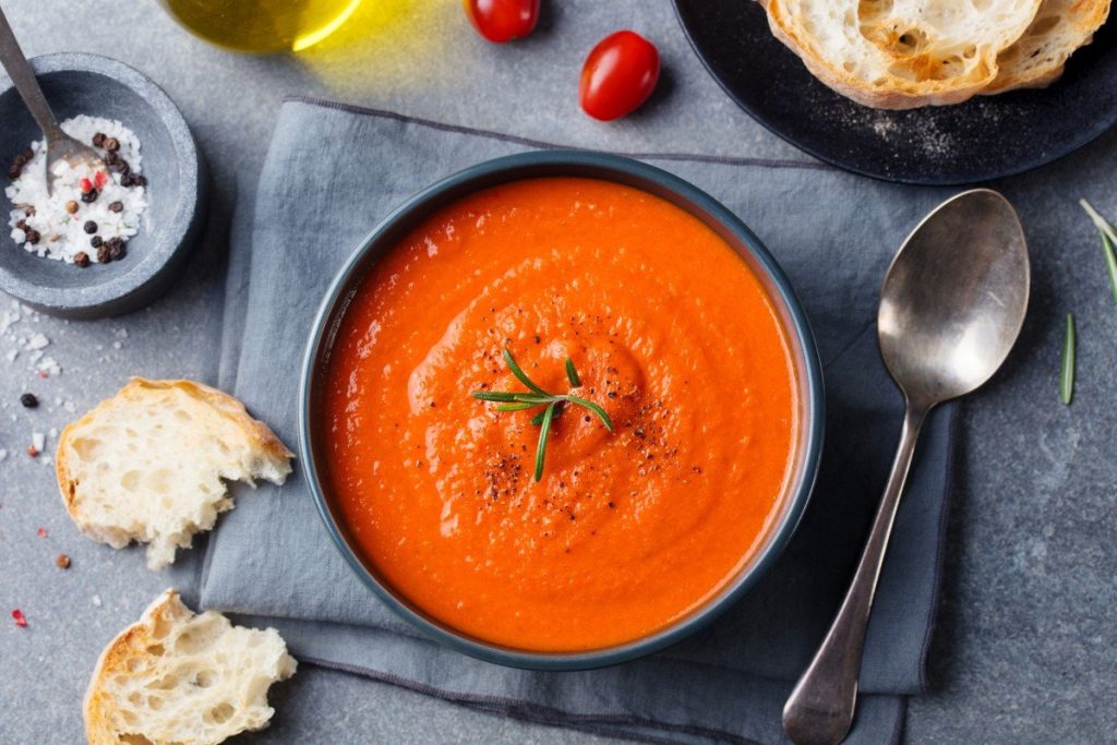 Der deutsche Koch fügt Püree zur Tomatensuppe hinzu. Mittagessen wie in einem guten Restaurant